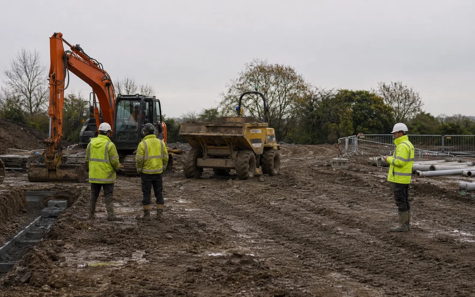 An excavator standing idle on a wet site.